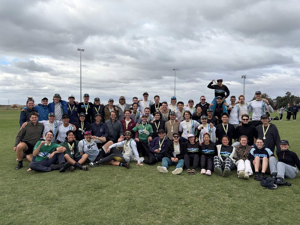 The team after the Australian Ultimate Championships, gathered in rows on a grass field wearing medals