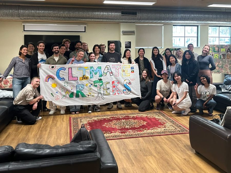 The Climate Writers group posing with a hand-painted Climate Writers banner in a common room