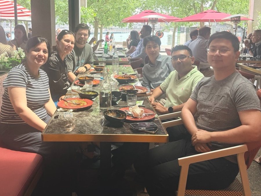 The 1H Team Award team sharing a meal at a long table in a waterside restaurant